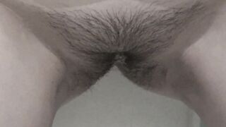 A milf with a hairy pussy pees while standing.